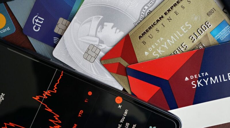 Karty płatnicze ułożone obok smartfona z wykresem finansowym na ekranie.