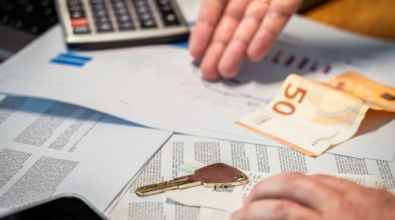 Klucz do mieszkania i banknot leżące na dokumentach finansowych