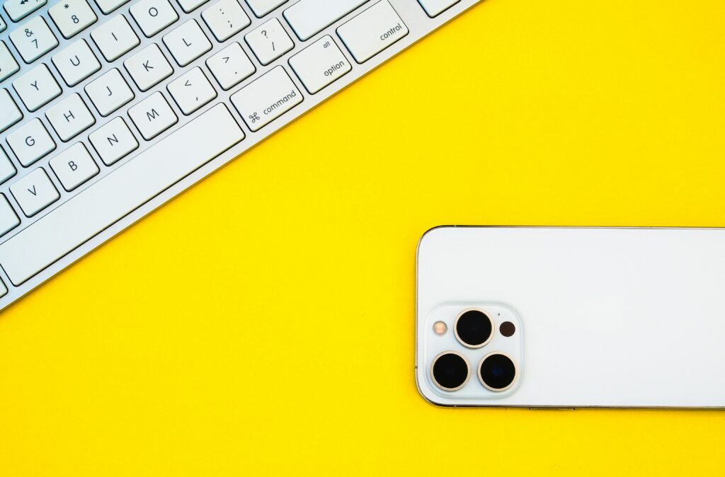 klawiatura i telefon marki Apple na żółtym tle