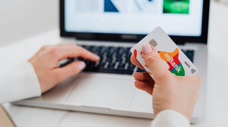 Osoba trzymająca kartę bankową mBank przed otwartym laptopem