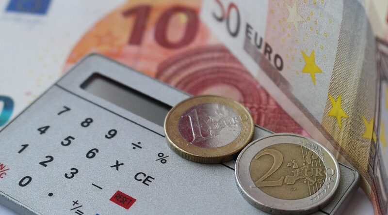 Kalkulator z monetami euro na tle banknotów euro.